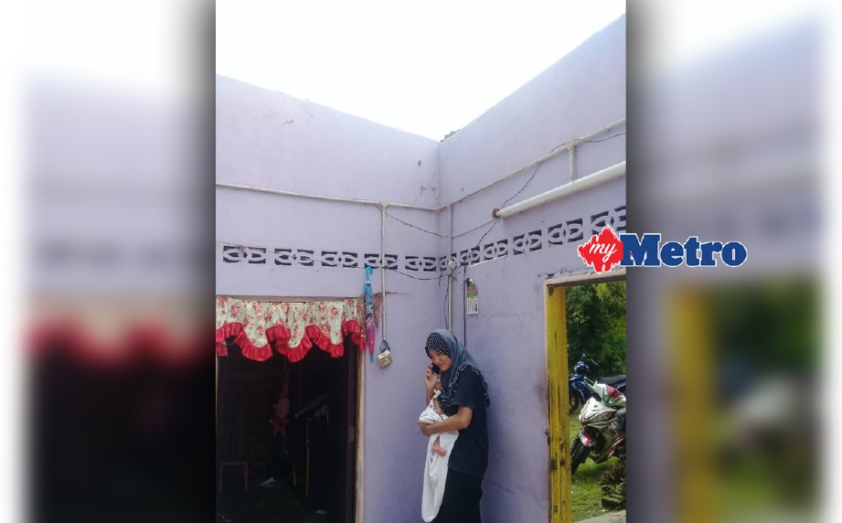Siti Ayu mendukung bayinya ketika rumahnya di Bakau Tua, Penaga, Kepala Batas, dilanda ribut, hari ini. FOTO Ihsan Pembaca