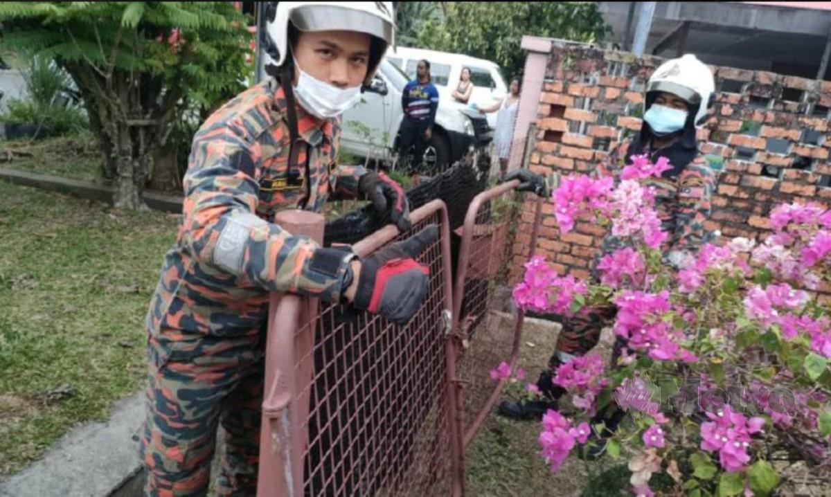ANGGOTA bomba membuka pagar besi rumah mangsa menggunakan peralatan khas. FOTO Ihsan Bomba.