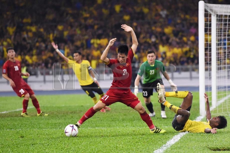 PERTAHANAN Vietnam Tran Dinh Trong (tengah) mengawal bola daripada dirampas pemain Malaysia. FOTO/AFP 