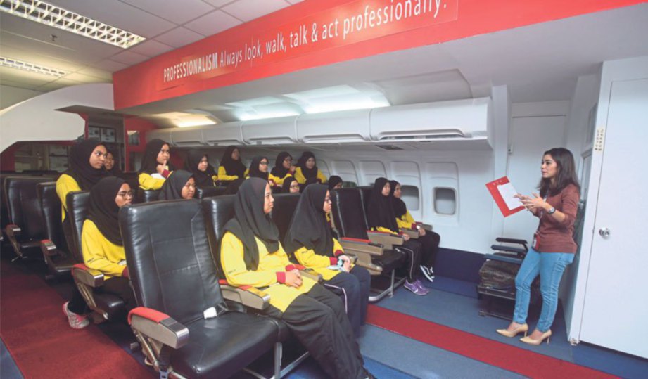 KAkitangan AACE Nur Zafirah memberi penerangan mengenai cara bekerja di dalam kapal terbang kepada pelajar.