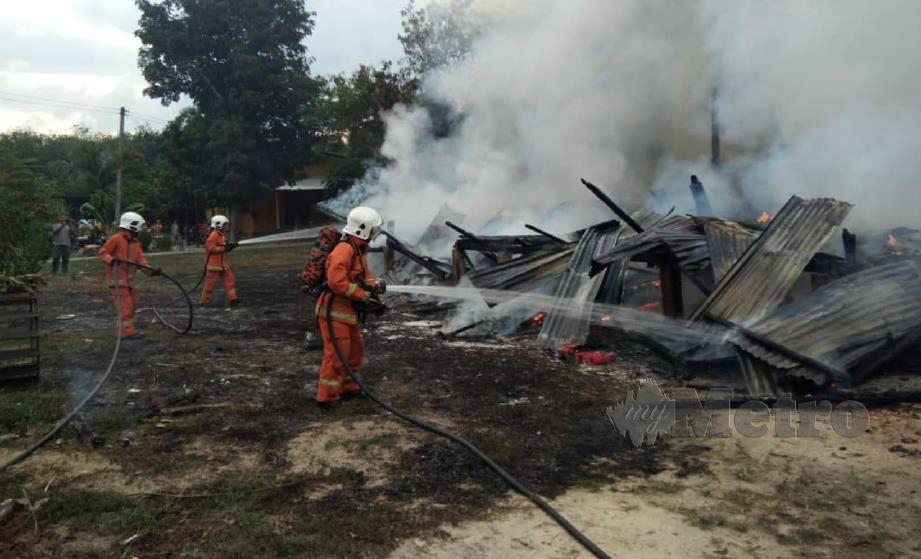 ANGGOTA bomba berusaha memadam kebakaran rumah sewa didiami tiga beranak di Kampung Senor, Meranti, Pasir Mas, hari ini. FOTO ihsan bomba. 