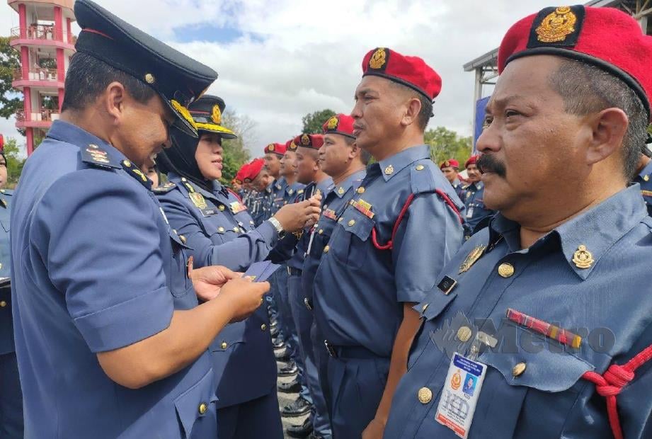SAYANI (kiri) memakaikan pangkat kepada pegawainya pada Majlis Perbarisan Tahunan JBPM Kedah di BBP Bukit Kayu Hitam. FOTO Zuliaty Zulkiffli.