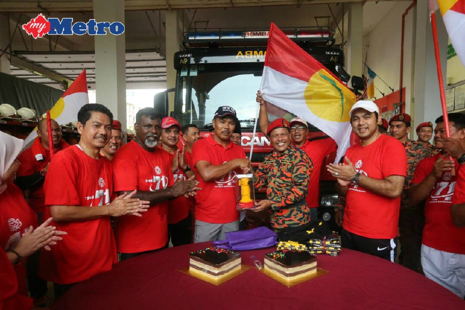 Mohd Zaidi (empat dari kiri) menyerahkan kek kepada Hadzi sempena Hari Bomba Sedunia. FOTO Eizairi Shamsudin 