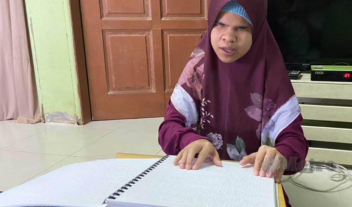 RAJA Noor Hani yang dilahirkan cacat penglihatan membaca naskhah al-Quran Braille ketika ditemui di rumahnya di Kampung Kubang Kacang. FOTO Hazira Ahmad Zaidi
