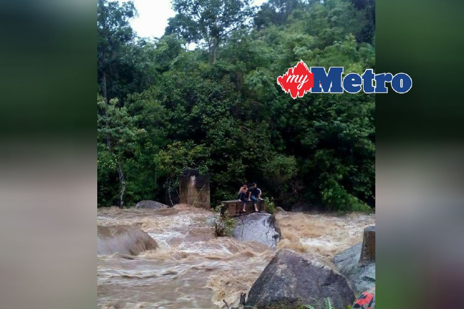 Dua sahabat terperangkap di tengah-tengah Sungai Lata Medang sebelum diselamatkan anggota bomba. FOTO ihsan bomba