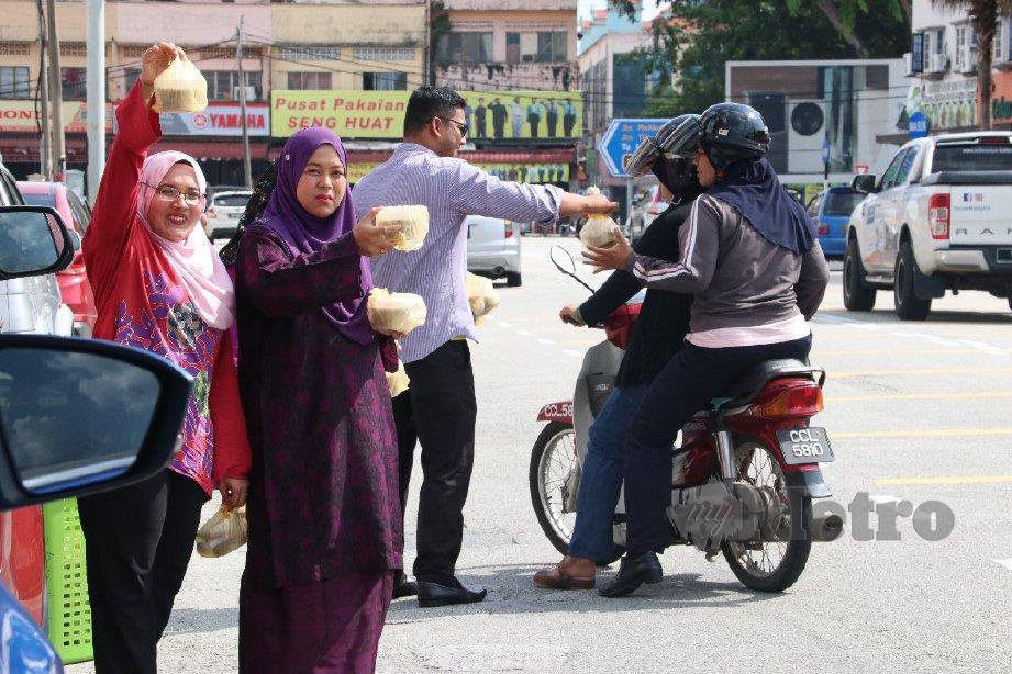 KAKITANGAN MARA Pahang berkumpul di tepi jalan untuk memberikan bubur lambuk percuma kepada orang ramai. FOTO Asrol Awang