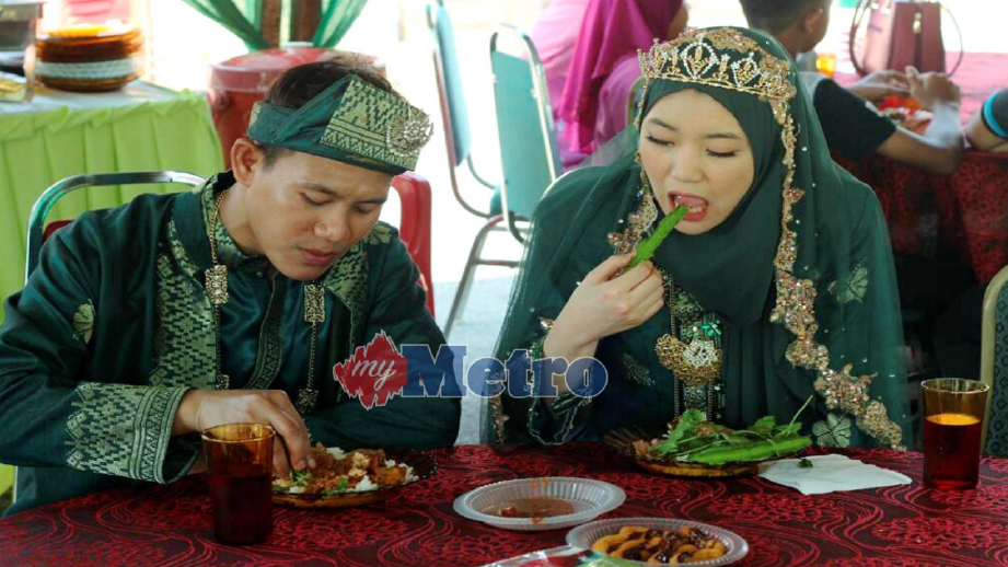 MUHAMAD Khalid bersama Anna makan nasi bersama budu dan ulam pada majlis resepsi mereka di Machang, hari ini. FOTO Nik Abdullah Nik Omar.