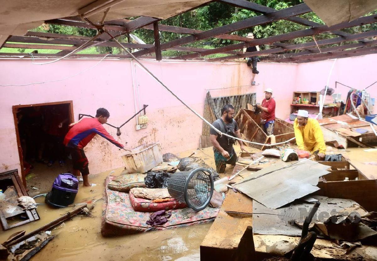 AHLI keluarga dan penduduk membersihkan rumah mangsa banjir di Kampung Belukar Bukit, Kuala Berang. FOTO GHAZALI KORI