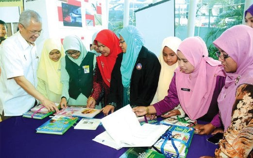MAHMUD (kiri) memperkatakan sesuatu mengenai buku berbahasa Inggeris kepada guru dan pelajar selepas majlis penyerahan ‘Books For Asia’.
