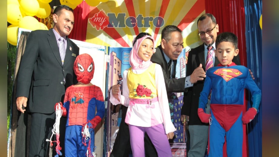MUHAMMAD Zahari (tengah) berkata sesuatu kepada murid yang memakai kostum Superman pada pelancaran program Nadi Ilmu Amalan Membaca (NILAM) di Sekolah Kebangsaan Kubang Kerian 3, Kota Bharu, hari ini. FOTO Syamsi Suhaimi