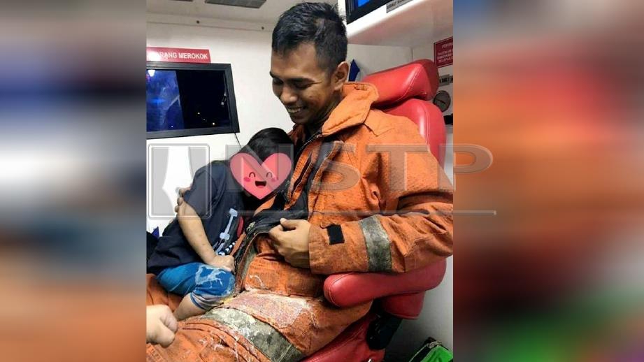 MUHAMMAD Azlan tersenyum selepas seorang kanak-kanak yang diselamatkan dalam kebakaran rumah di Taman Arked, Dengkil, muntah di atas bajunya, hari ini dan gambar itu tular di media sosial. 