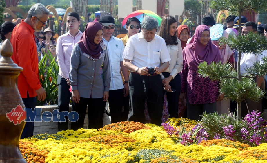 SULTAN Sharafuddin Idris Shah merakamkan gambar bunga-bungaan ketika melawat ke pameran selepas merasmikan Festival Bunga Dan Taman Diraja Putrajaya 2018 di Presint 4, Putrajaya, hari ini. Turut kelihatan Tengku Permaisuri Norashikin, Khalid (kiri) dan Ketua Pegawai Eksekutif Putrajaya Floria Sdn Bhd, Haslinda Khalid. FOTO Mohd Fadli Hamzah.