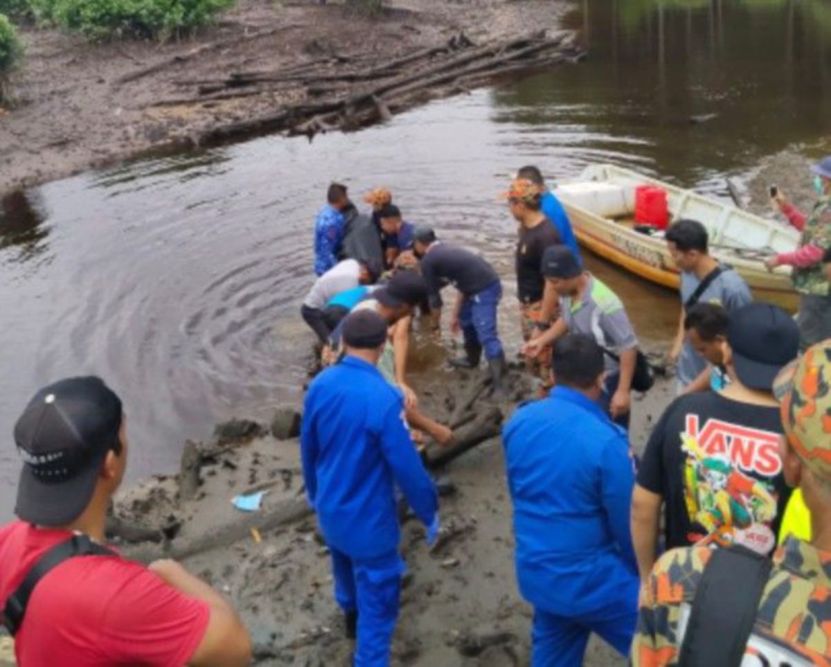 ANGGOTA bomba mengangkat mayat Mohamad Burhan di tebing Sungai Karang, Pontian. FOTO Togi Marzuki.