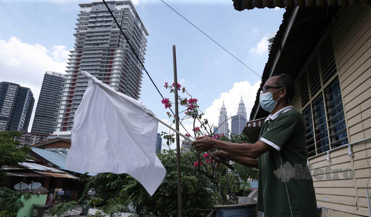 BUSTAMI menurunkan bendera putih yang dipasangnya pada Khamis lalu selepas menerima sumbangan daripada IPD Dang Wangi. FOTO Aziah Azmee