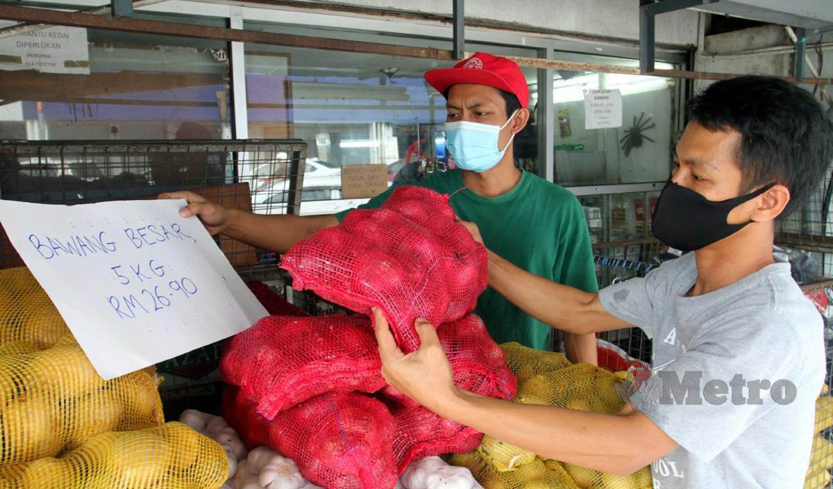 MUHD Ridzuan (kiri) bersama pekerjanya menunjukkan tanda harga bawang besar 5 kg berharga RM26.90 yang dijual di kedainya susulan kesukaran mendapat bekalan serta harga yang terlalu tinggi di Kampung Melayu Majidee, Johor Bahru. FOTO Zain Ahmed