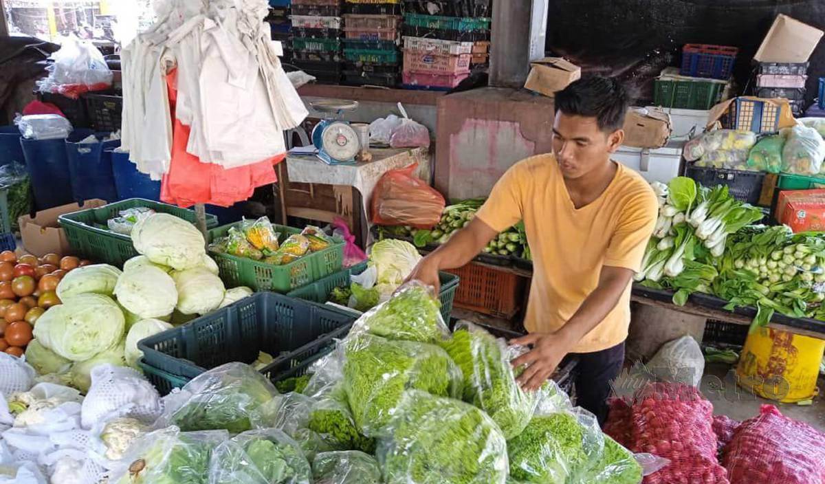 PEKERJA di kedai Mohamat Embong sedang menyusun sayur yang dijual di Pasar Cabang Tiga. FOTO Faizul Azlan Razak