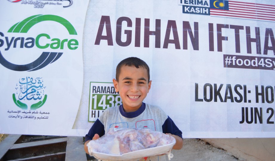 SENYUMAN terukir sebaik menerima bantuan makanan daripada sukarelawan Syria Care. 