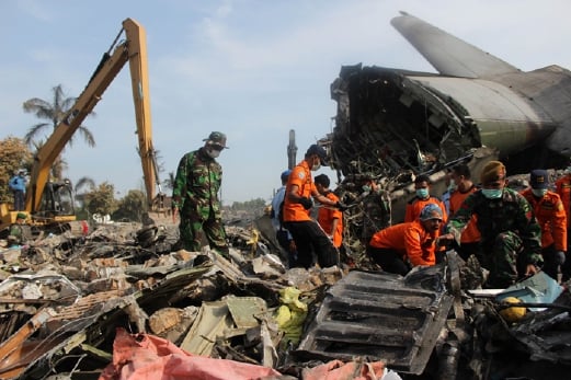 anggota pasukan penyelamat menyelongkar serpihan pesawat bagi mencari mencari mangsa manakala jentera berat membersihkan runtuhan bangunan. - Foto  AFP 