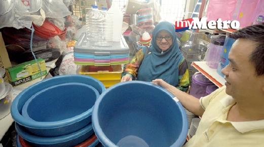 Narisa Abdul Rahim, 45 (kiri) memilih bekas takungan air di sebuah kedai di Kangar sebagai persediaan menyimpan air jika air dicatu di Perlis berikutan paras takungan air di Empangan Timah Tasoh semakin kritikal. - Foto Fail