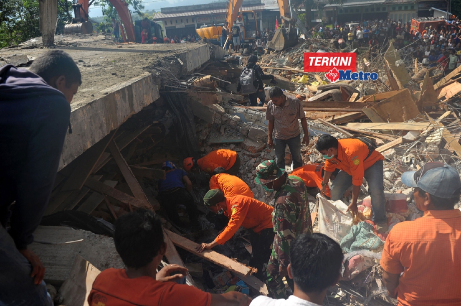 Anggota penyelamat membongkar runtuhan di sebuah bangunan di daerah Pidie Jaya bagi mengeluarkan mangsa yang tertimbus. - Foto AFP/ CHAIDEER MAHYUDDIN