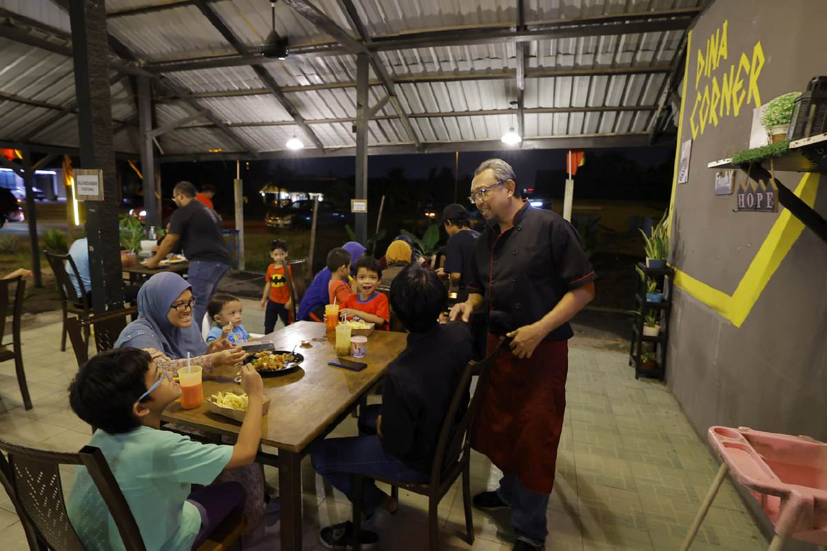 MOHAMAD Farid beramah mesra dengan pelanggan setia di restorannya, Dina Corner di Kampung Semarang, Dengkil. FOTO BERNAMA