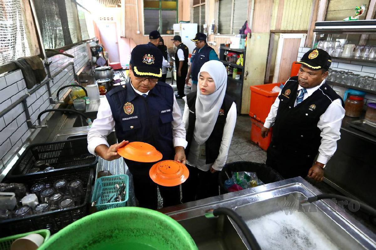 PEGAWAI penguat kuasa JKNT memeriksa keadaan sebuah kedai makan dapam Operasi Cakna Penguatkuasaan Undang-undang Kesihatan Awam Peringkat Negeri Terengganu d di Seberang Takir hari ini. FOTO Ghazali Kori.