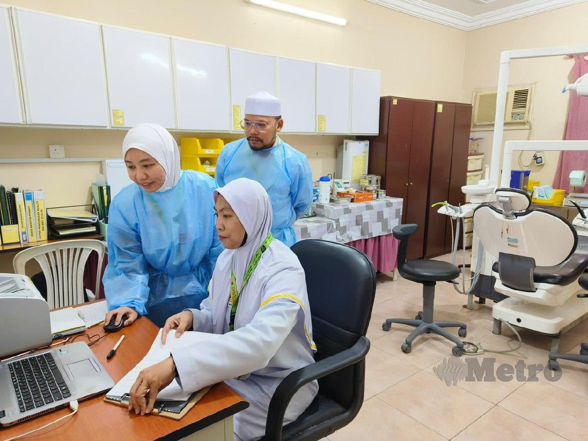 DR Siti Umairah sedang menyemak rekod pesakit sambil dibantu Nur Syuhana (duduk) dan Al Hafiz Meor di kliniknya, baru-baru ini. FOTO Husain Jahit