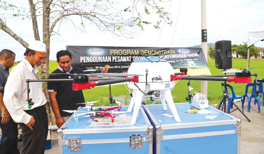 PESAWAT dron digunakan untuk menyembur racun dan memantau tanaman di sawah.