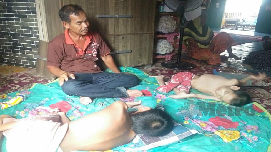 Mohd Zain bersama dua anaknya yang menghidap cerebral palsy di rumahnya di Kampung Kok Keli 1, Tumpat. Foto Rohana Idris 