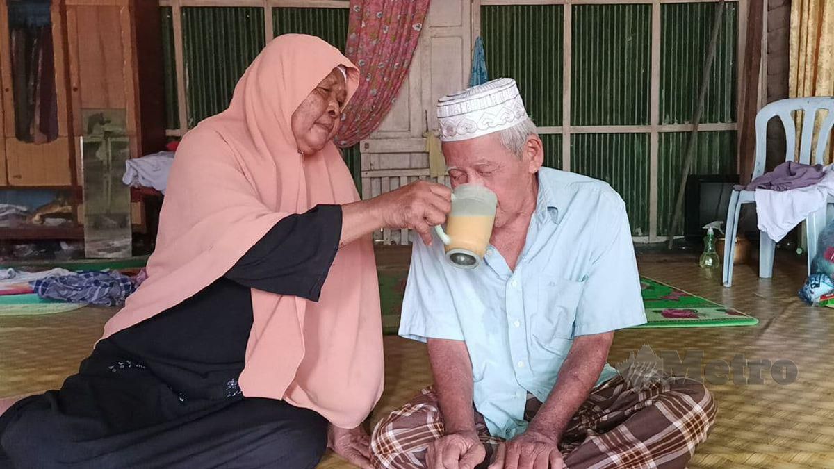 MEK Som membantu Che Wel minum di rumah mereka di Kampung Kok Bedullah. FOTO Siti Rohana Idris