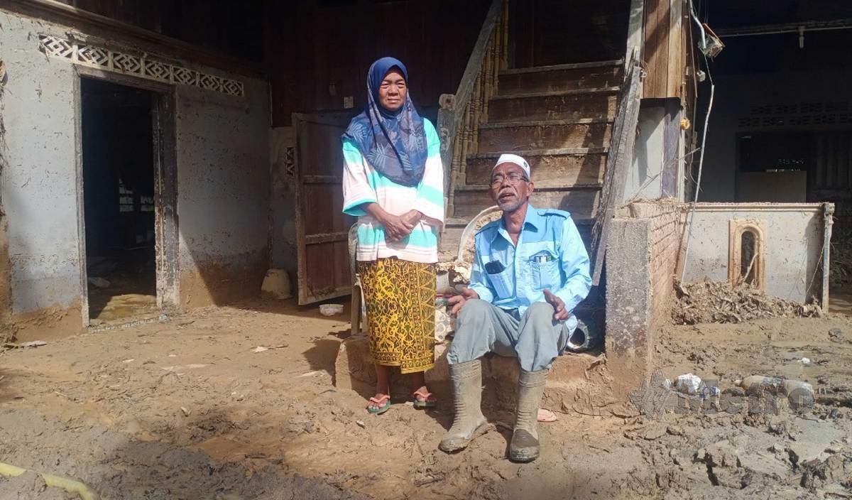 ABDULLAH dan isterinya Che Liah berada di hadapan rumah mereka yang rosak teruk di Kampung Masjid Iboi akibat banjir dan kepala air 4 Julai lalu. FOTO Noorazura Abdul Rahman