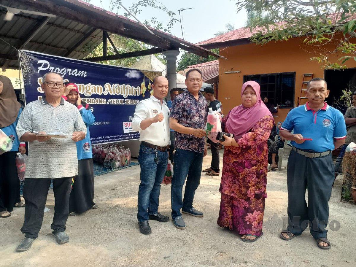 Che Rohayu menerima sumbangan biskut raya dari wakil Pasar Raya Supermas, Mohd Rozi Mohd Zali dalam majlis agihan yang dibuat di Kampung Kajang Sebidang. FOTO SITI ROHANA IDRIS