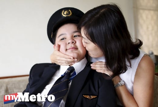 Ivy Loi, isteri pembantu juruterbang pesawat MH17 Eugene Choo, mencium anaknya Scott Choo, 12, yang memakai seragam bapanya di rumah mereka di Seremban. - Foto REUTERS