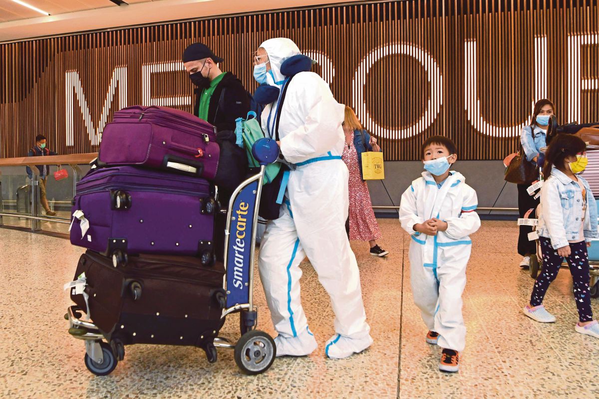 PENUMPANG memakai pakaian perlindungan diri ketika tiba di Lapangan Terbang Tullamarine, Melbourne. FOTO AFP