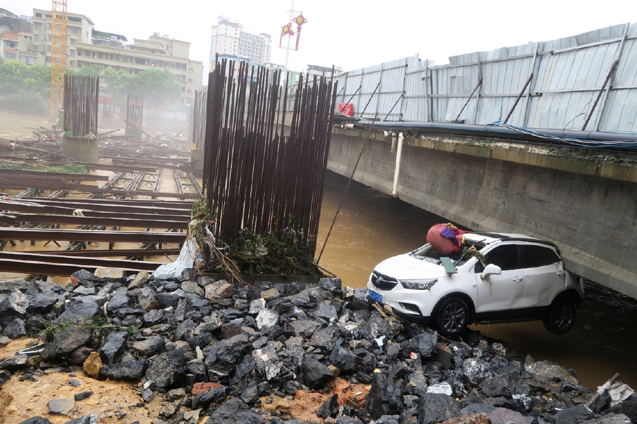 Kereta yang tersangkut di bawah jambatan di daerah Quanzhou, wilayah Guangxi. - Foto REUTERS