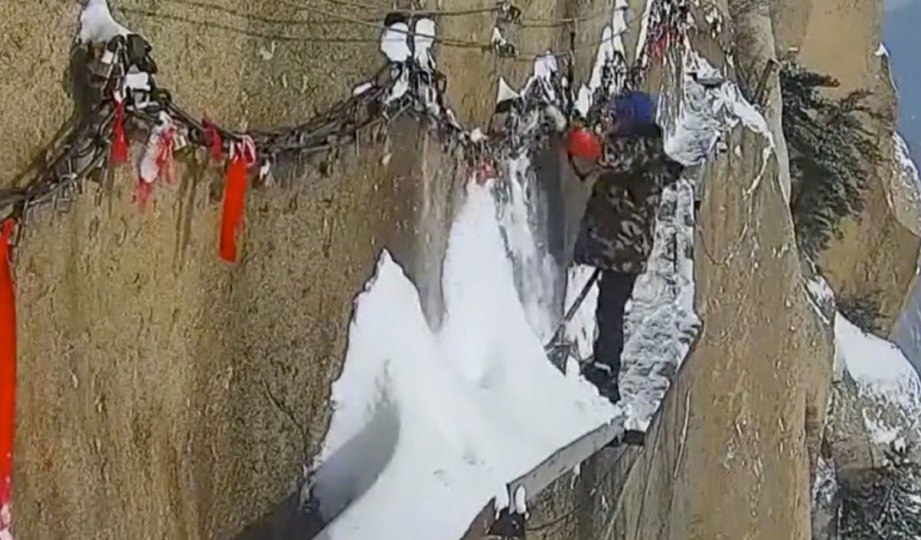 SEORANG petugas membersihkan salji di laluan sempit yang terdapat di Gunung Huashan di wilayah Shaanxi, China. FOTO News.163.com