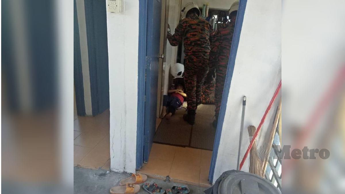 ANGGOTA bomba menangkap ular yang menyelinap masuk ke dalam baju kanak-kanak di Kuarters Balai Polis Ayer Baloi, hari ini. FOTO ihsan bomba