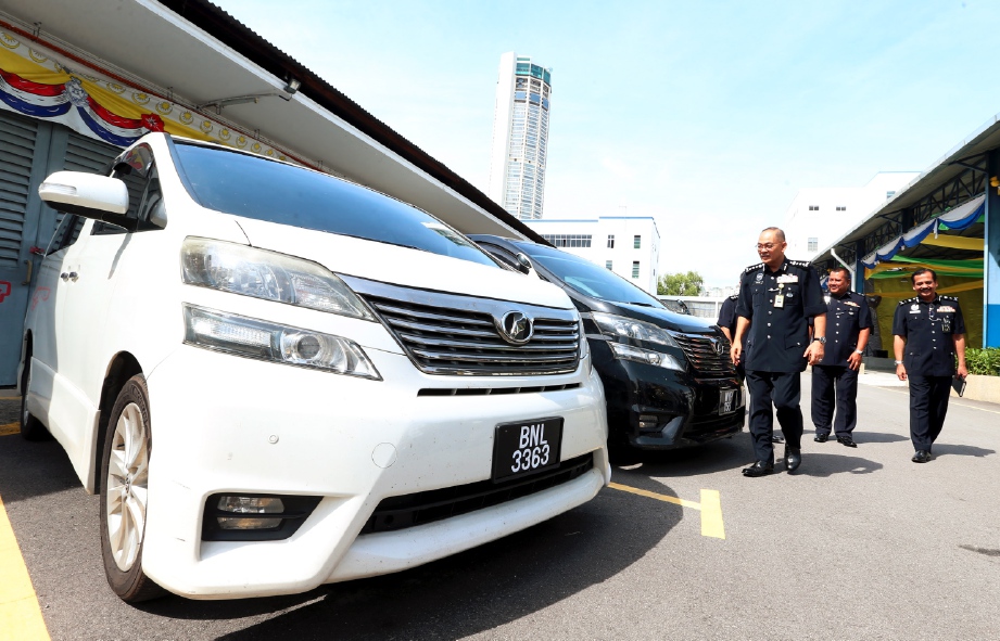 Abdul Ghafar (kiri) melihat kenderaan mewah yang dirampas oleh polis ketika sidang media di Ibu Pejabat Polis Kontinjen (IPK) Pulau Pinang, hari ini. FOTO Mikail Ong
