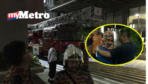 Wanita yang cuba terjun menutup kepala menggunakan baju bomba dan terus ditenangkan anggota bomba selepas diselamatkan. FOTO ihsan bomba