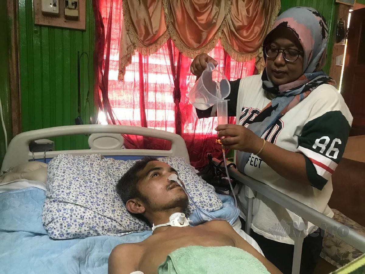 Norhashehini menguruskan suaminya, Syafuddin yang terlantar akibat kemalangan jalan raya ketika ditemui di Kampung Padang Enggang. FOTO HAZIRA AHMAD ZAIDI