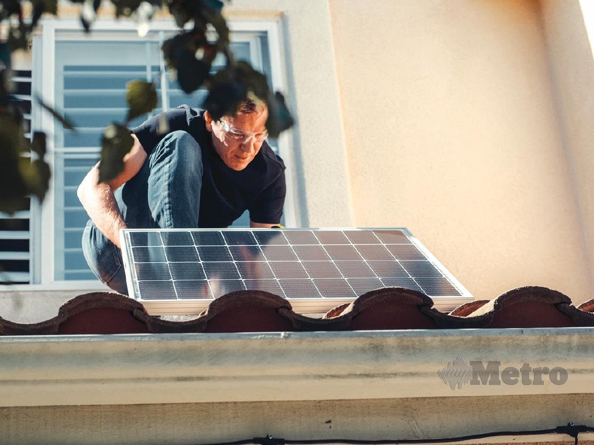 MEMASANG panel solar di atas bumbung rumah.