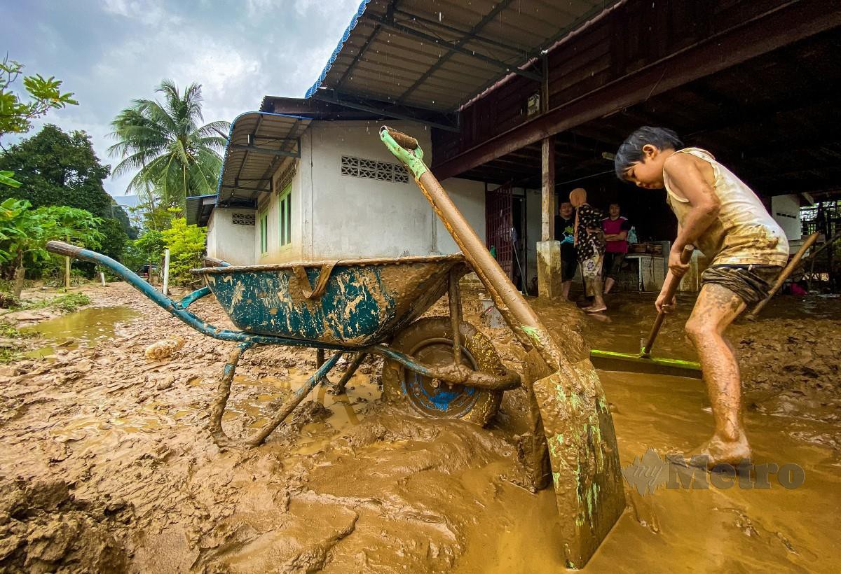 KANAK-KANAK membantu keluarganya membersihkan lumpur di rumah mereka di Yan Kechil, di sini yang ditenggelami banjir akibat kepala air di Gunung Jerai. FOTO Luqman Hakim Zubir.