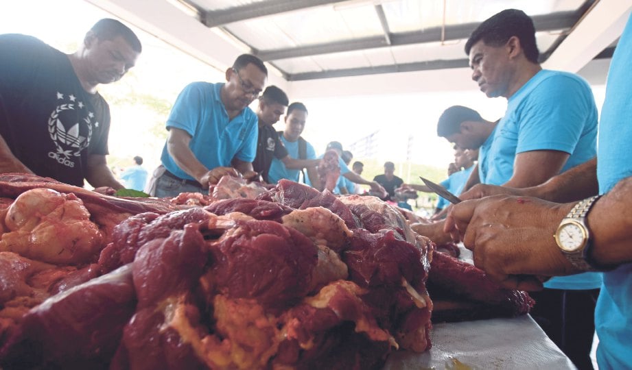 ANGGOTA polis bergotong-royong melapah dan memotong daging lembu korban pada majlis Ibadah Korban dan Akikah Ibu Pejabat Polis Daerah (IPD) Shah Alam, tahun lalu. - Gambar hiasan