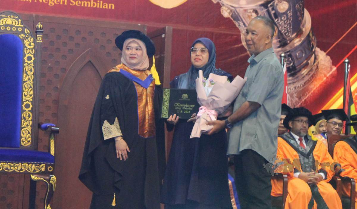 FADHLINA (kiri) menyampaikan diploma secara anumerta kepada Aminah bagi pihak anaknya, Nur Adlina pada Majlis Konvokesyen Kolej Vokasional Kali Ke-8 di USIM Nilai. FOTO Mohd Amin Jalil
