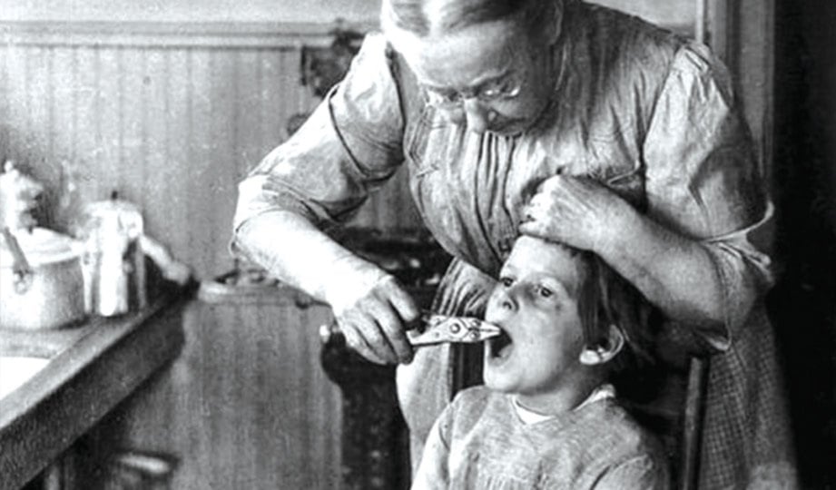 SEORANG wanita mencabut gigi seorang budak lelaki pada tahun 1920-an di Amerika.