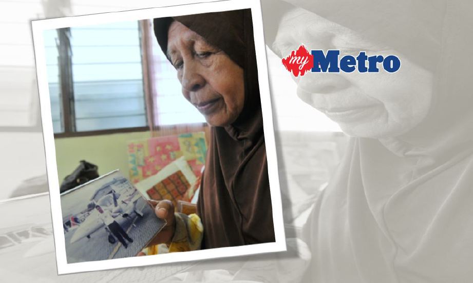 ROHANI Che Embi, 72, melihat foto anak saudaranya Allahyarham Muhammad Firdaus Abdul Rahim iaitu Pembantu Juruterbang MH17, ketika di temuramah di kediamannya di Teluk Intan, Perak. FOTO Bernama