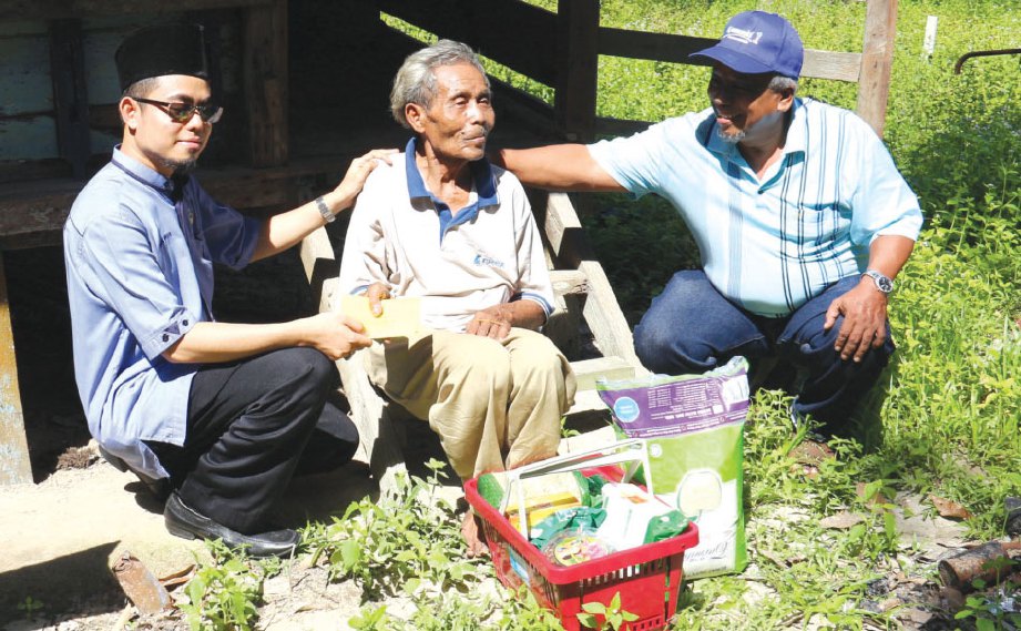 KHARUL Anwar (kiri) dan Salamon  menyampaikan sumbangan kepada Pak Din di pondoknya, baru-baru ini.