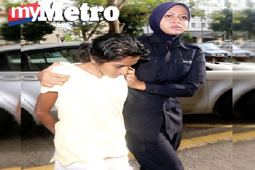 Malathi diiringi anggota polis selepas mengaku tidak bersalah mendera anak perempuannya. FOTO Danial Saad