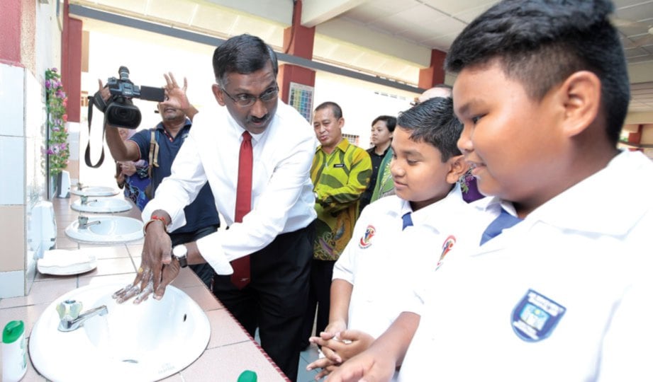 KAMALANATHAN menunjukkan cara betul mencuci tangan kepada murid SK Seksyen 7, Shah Alam.