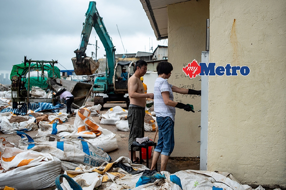 PENDUDUK Hong Kong mula membersihkan persekiran kawasan kediaman mereka yang dilanda Taufan Mangkhut. FOTO/AFP 